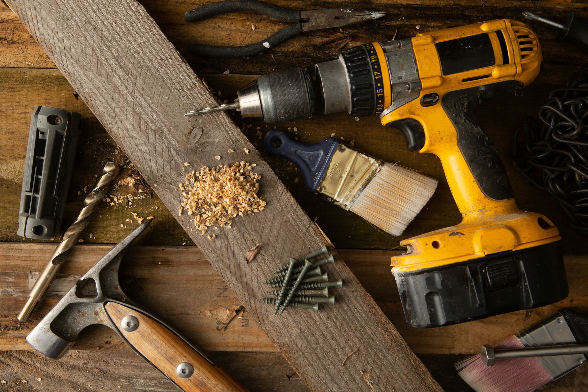 Workbench flat lay with hand tools, wood plank, and screws mid-project
